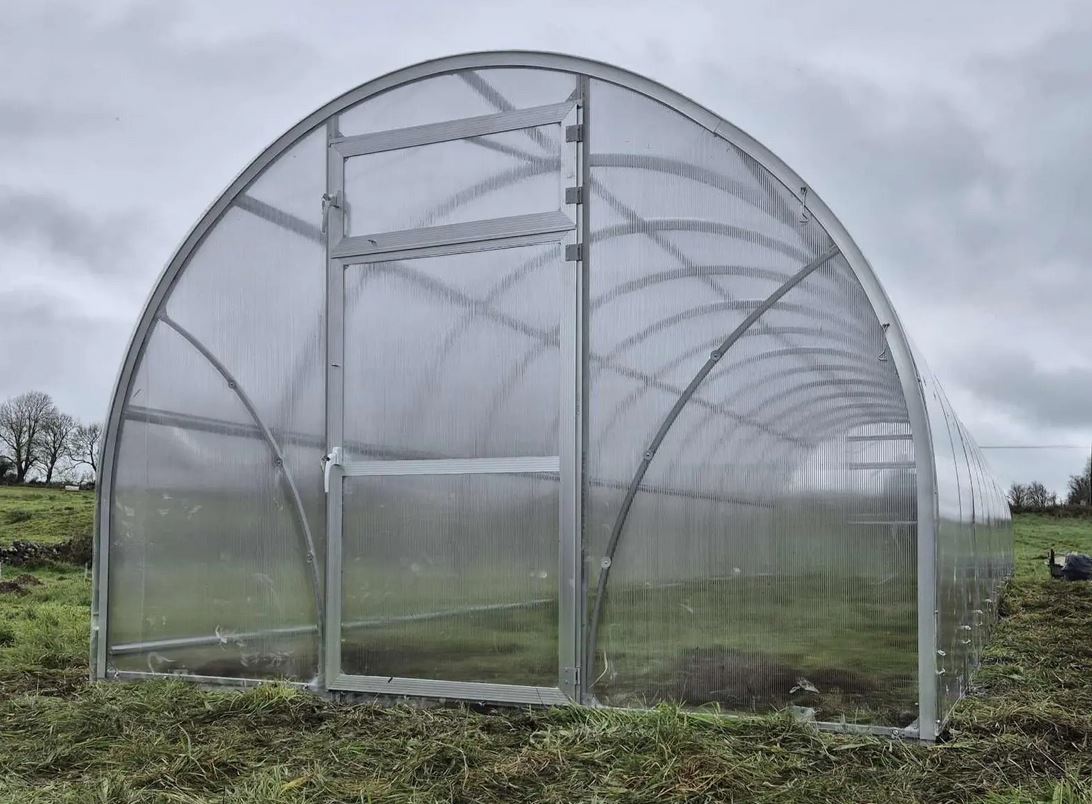 Szklarnia PREMIUM Sigma EVO 3×8 m, poliwęglan 6 mm Szklarnia PREMIUM Sigma EVO 3×12 m z poliwęglanu – widok frontu, drzwi i wzmocnionej konstrukcji łukowej